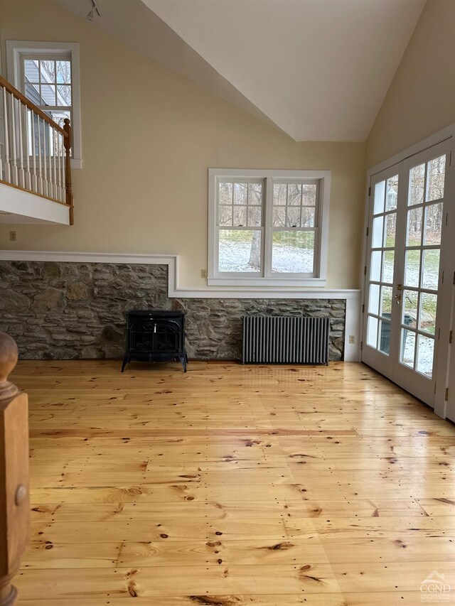 477 Fog Hill Rd, Austerlitz, NY 12017 - living room featuring radiator heating unit, a wood stove, vaulted ceiling, wood-type flooring, and plenty of natural light
