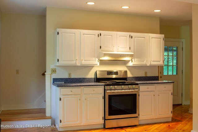 477 Fog Hill Rd, Austerlitz, NY 12017 - kitchen featuring stainless steel gas range oven, under cabinet range hood, dark countertops, white cabinetry, and light wood-style flooring