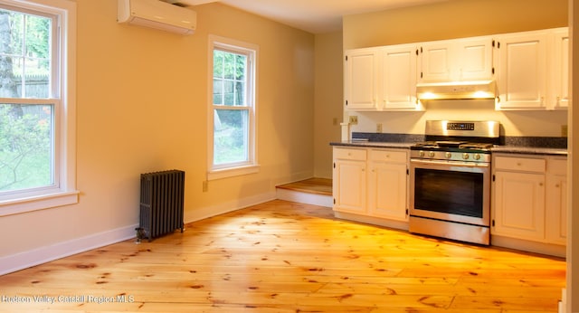 477 Fog Hill Rd, Austerlitz, NY 12017 - kitchen featuring radiator, an AC wall unit, gas range, light wood finished floors, and under cabinet range hood