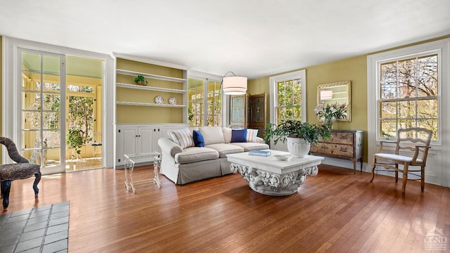 living room featuring wood-type flooring, plenty of natural light, and built in features