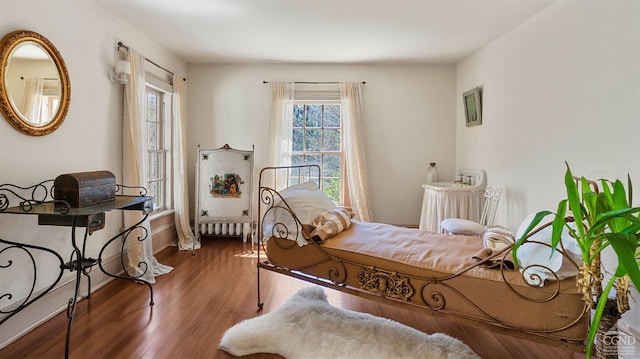 bedroom featuring wood finished floors, baseboards, and radiator heating unit