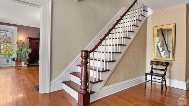 staircase featuring wood finished floors, wallpapered walls, and baseboards