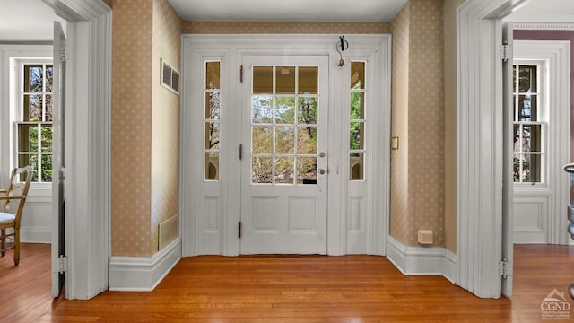 doorway to outside featuring light wood finished floors and wallpapered walls