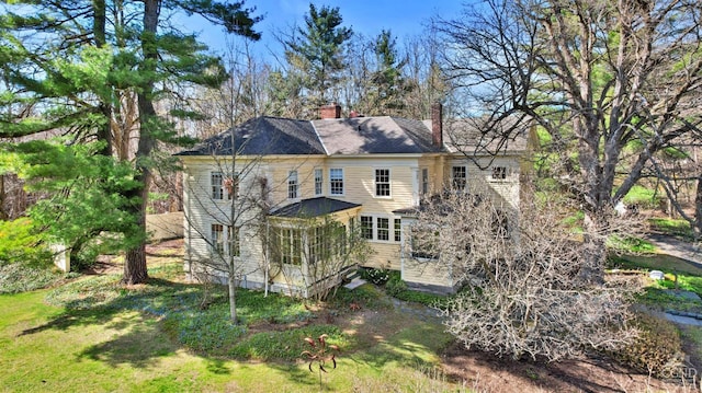 rear view of property with a chimney and a sunroom