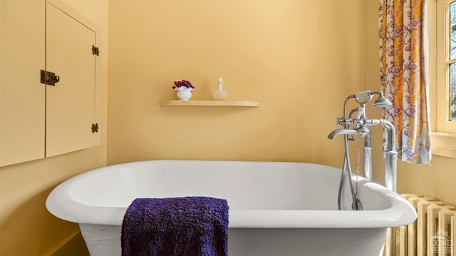 full bathroom with radiator and a freestanding bath