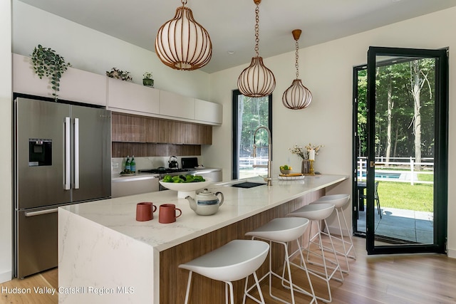 8 Accurso Rd, Saugerties, NY 12477 - kitchen featuring modern cabinets, pendant lighting, a breakfast bar, stainless steel refrigerator with ice dispenser, and light wood finished floors