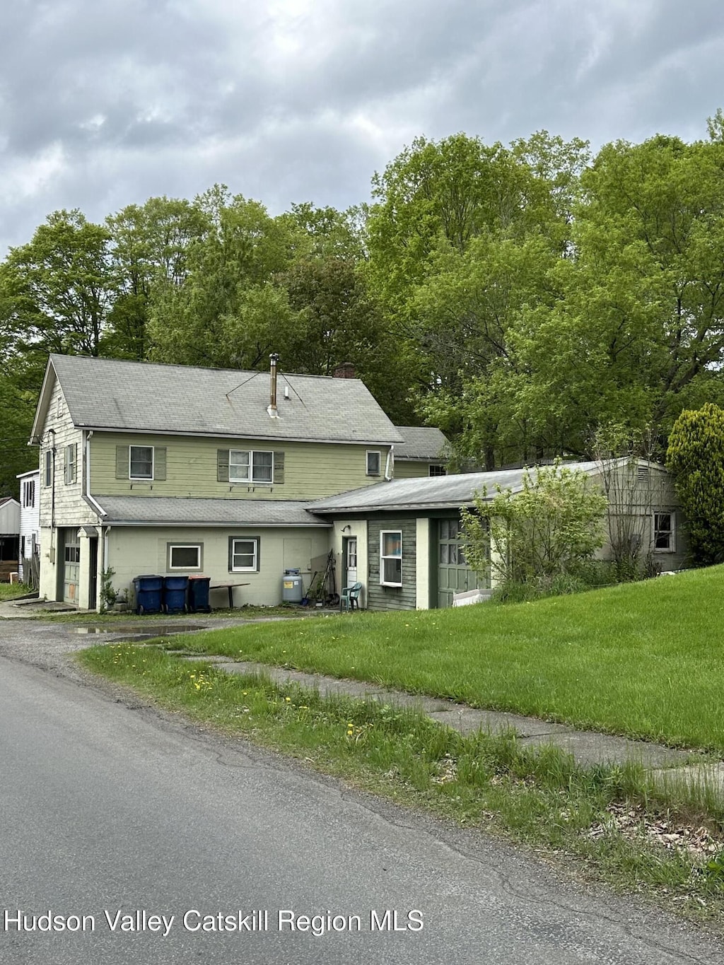 view of front of house featuring a front yard, driveway, view of wooded area, and an attached garage