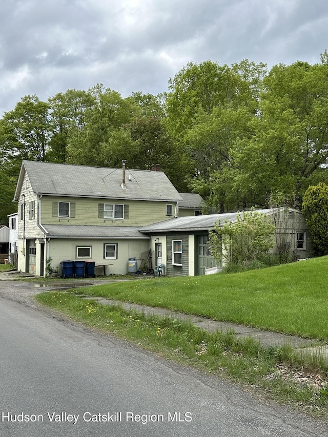 view of front of house featuring a front yard, driveway, view of wooded area, and an attached garage