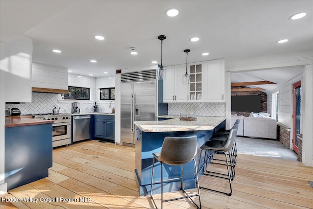 kitchen featuring kitchen peninsula, decorative light fixtures, light hardwood / wood-style flooring, high quality appliances, and white cabinetry