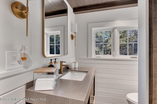 bathroom featuring beamed ceiling, toilet, wooden ceiling, and wooden walls