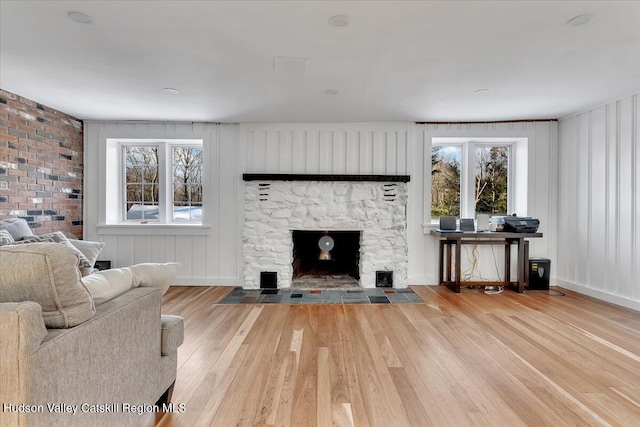 unfurnished living room featuring light hardwood / wood-style floors and a stone fireplace