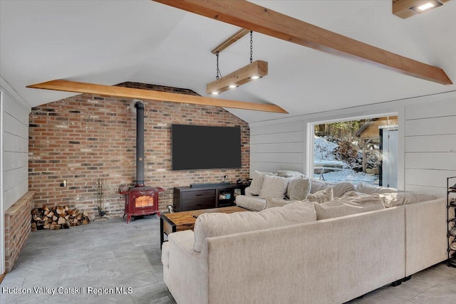 living room featuring lofted ceiling with beams, a wood stove, and brick wall