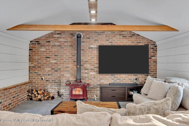 living room with vaulted ceiling with beams, a wood stove, and brick wall