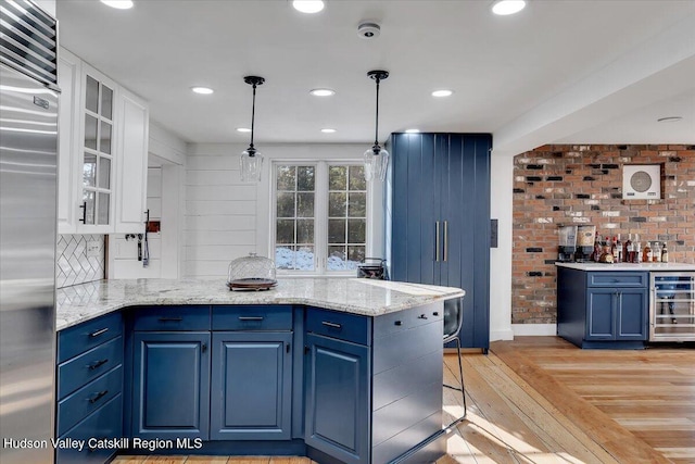 kitchen with beverage cooler, built in fridge, blue cabinets, light hardwood / wood-style floors, and decorative light fixtures