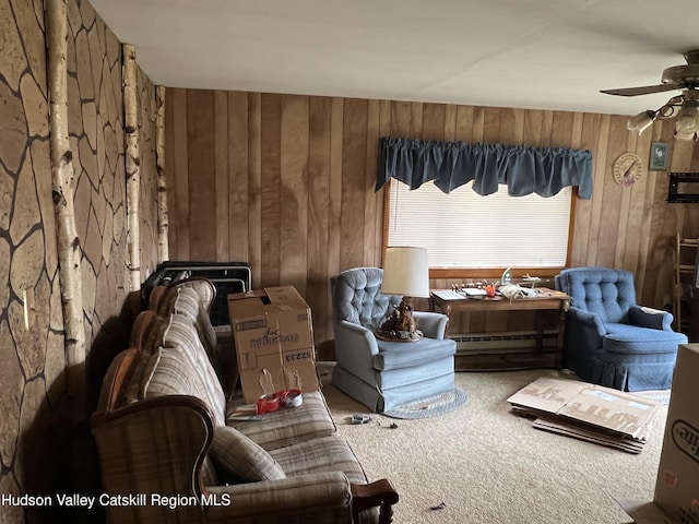 sitting room with carpet flooring, ceiling fan, wood walls, and a baseboard heating unit