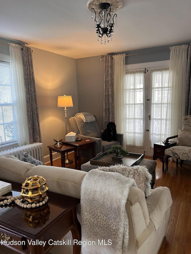 living room featuring french doors, radiator, wood finished floors, and a chandelier