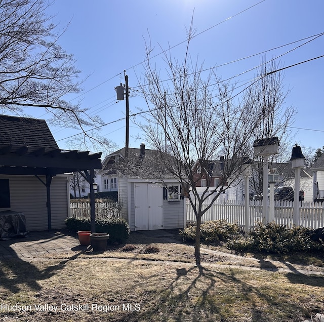 view of yard featuring an outbuilding, a pergola, and fence