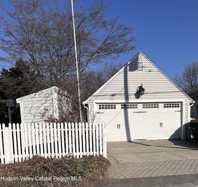 view of side of home featuring a detached garage, an outbuilding, and fence