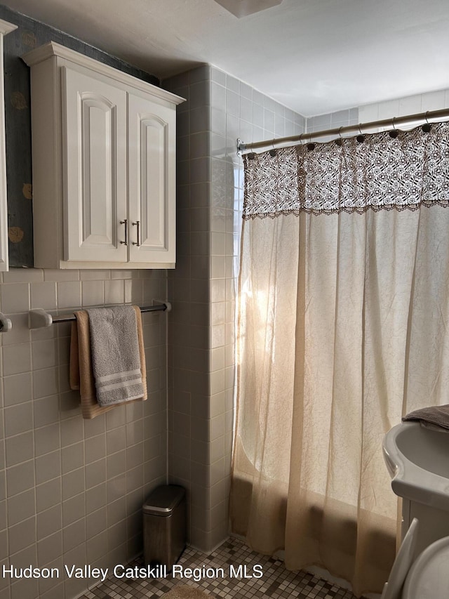 full bathroom with tile walls and shower / bath combo with shower curtain