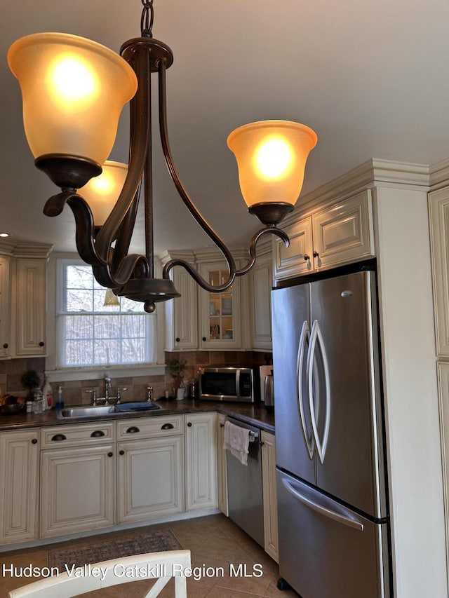 kitchen with light tile patterned floors, a sink, glass insert cabinets, appliances with stainless steel finishes, and dark countertops