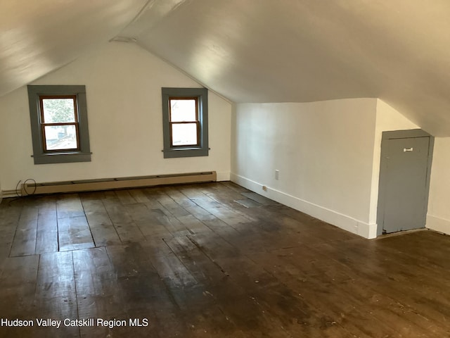 additional living space with a healthy amount of sunlight, lofted ceiling, a baseboard heating unit, and dark hardwood / wood-style flooring