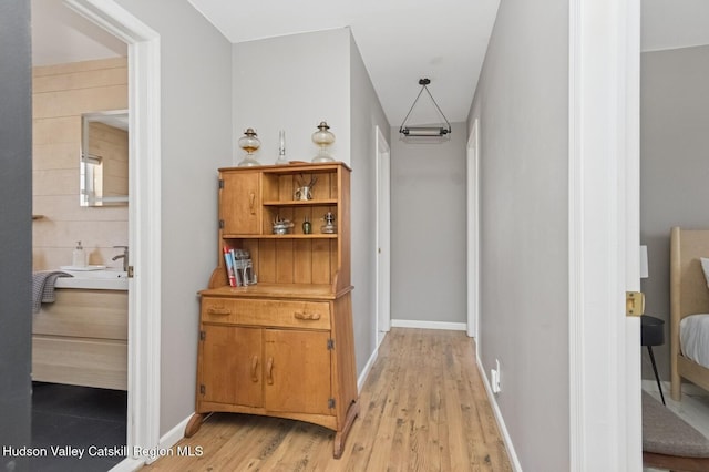 hallway featuring light wood-style floors and baseboards
