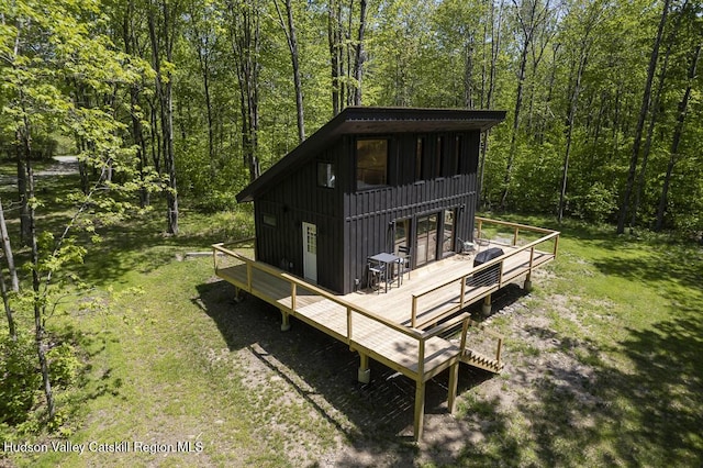 exterior space featuring board and batten siding, a forest view, and a deck