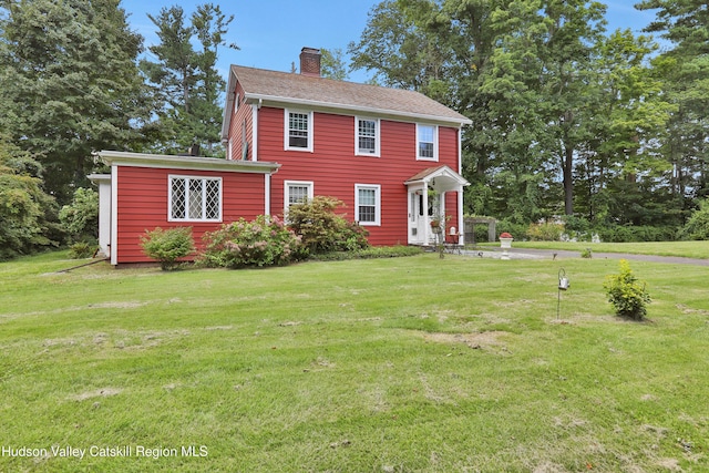 colonial house with a chimney and a front yard