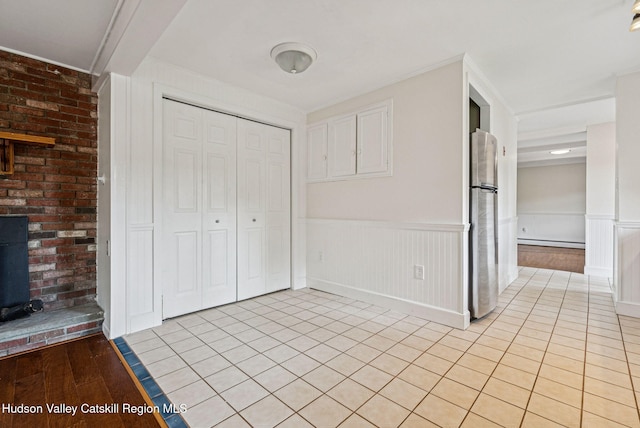 6 Stevens Ct, Saugerties, NY 12477 - unfurnished bedroom with freestanding refrigerator, a baseboard radiator, a wainscoted wall, a closet, and light tile patterned flooring