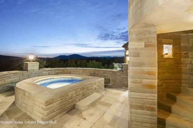 pool at dusk with an in ground hot tub and a mountain view