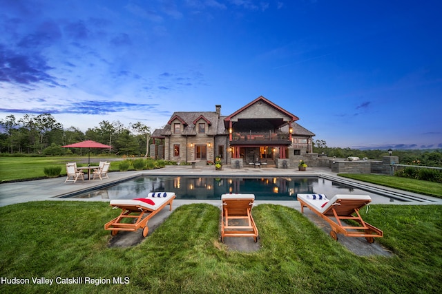 pool at dusk with a lawn and a patio area