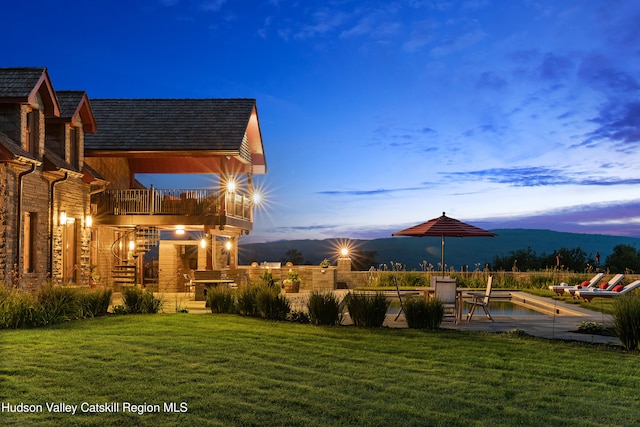 yard at dusk with a mountain view and a balcony