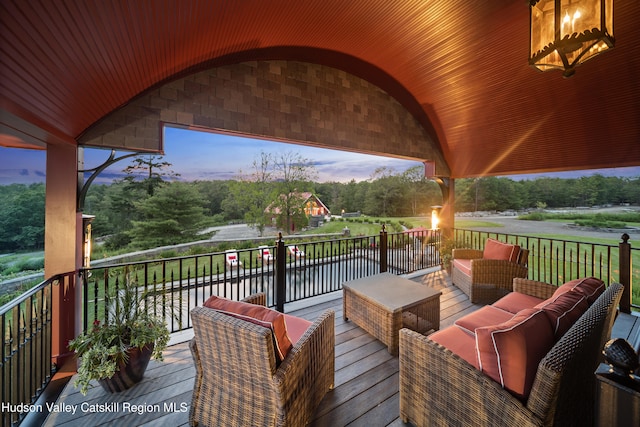 deck at dusk featuring an outdoor hangout area and a water view