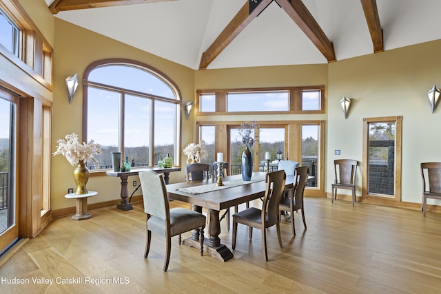 dining area with beam ceiling, light wood-type flooring, high vaulted ceiling, and french doors