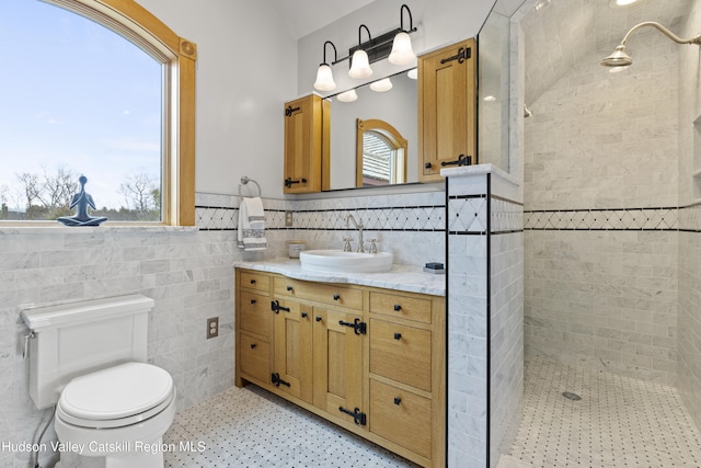 bathroom featuring a tile shower, vanity, a healthy amount of sunlight, and tile walls