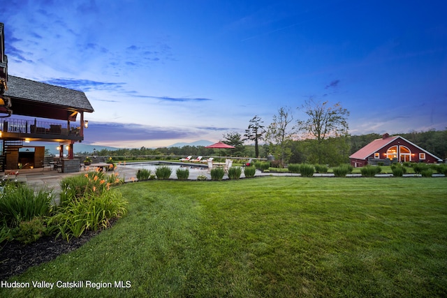 yard at dusk with a water view and a patio