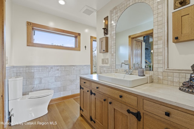 bathroom with vanity, toilet, wood-type flooring, and tile walls