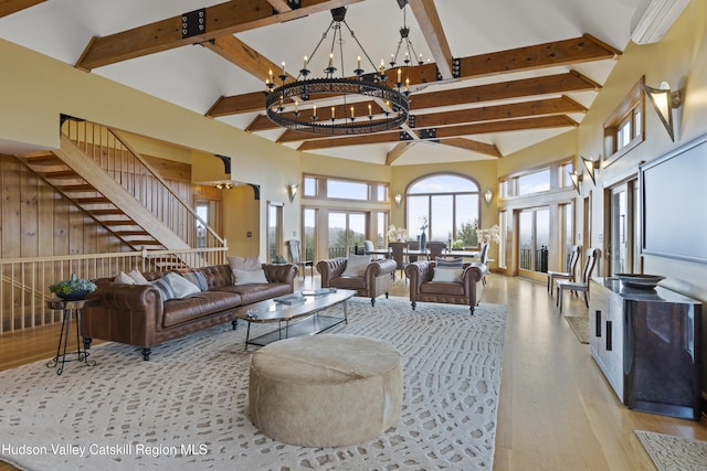 living room featuring beamed ceiling, light hardwood / wood-style flooring, high vaulted ceiling, and a chandelier