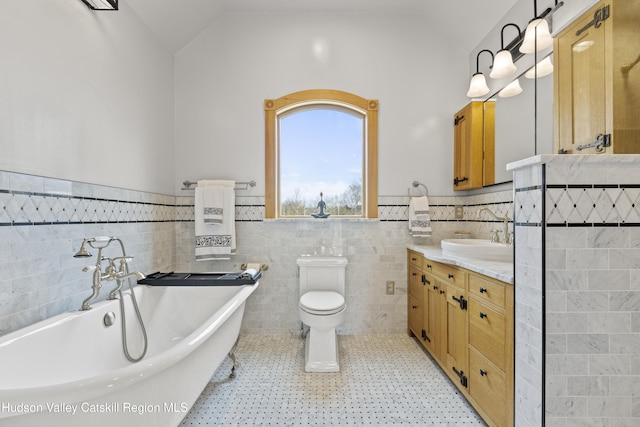 bathroom with vanity, a tub to relax in, tile walls, and vaulted ceiling