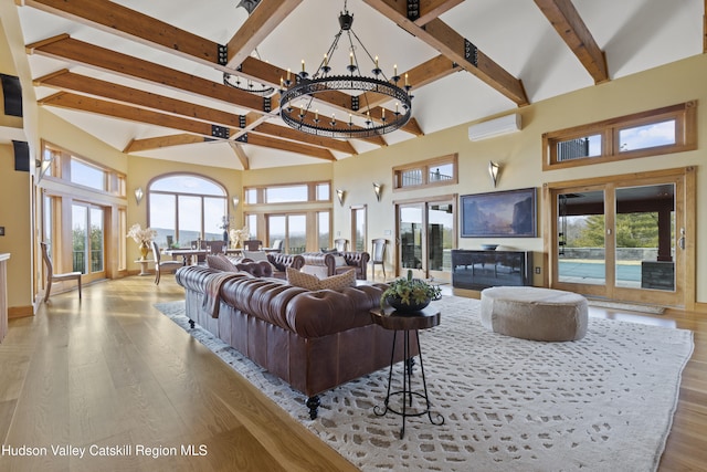 living room with light hardwood / wood-style floors, a notable chandelier, a healthy amount of sunlight, and a towering ceiling