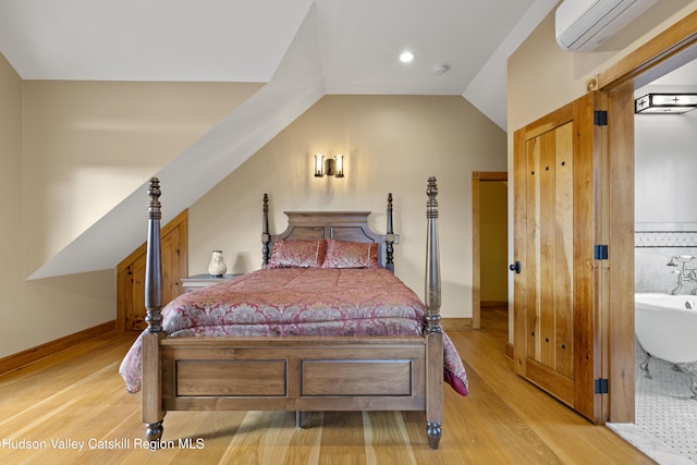 bedroom with light hardwood / wood-style floors, a wall mounted AC, and lofted ceiling