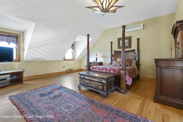 bedroom featuring a wall mounted air conditioner, lofted ceiling, and light wood-type flooring