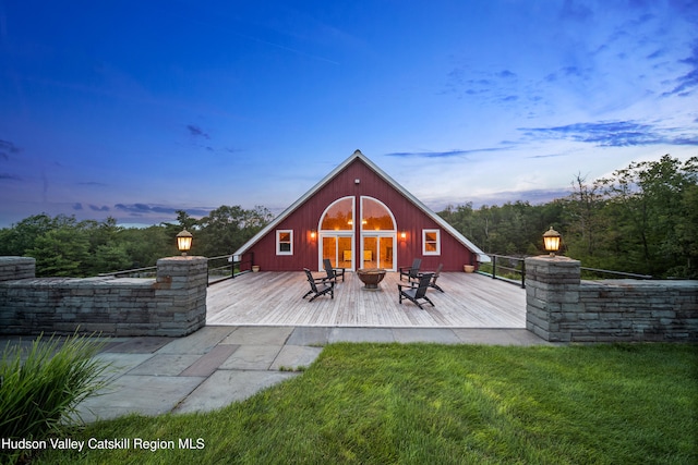 back house at dusk with a yard, an outdoor fire pit, and a wooden deck