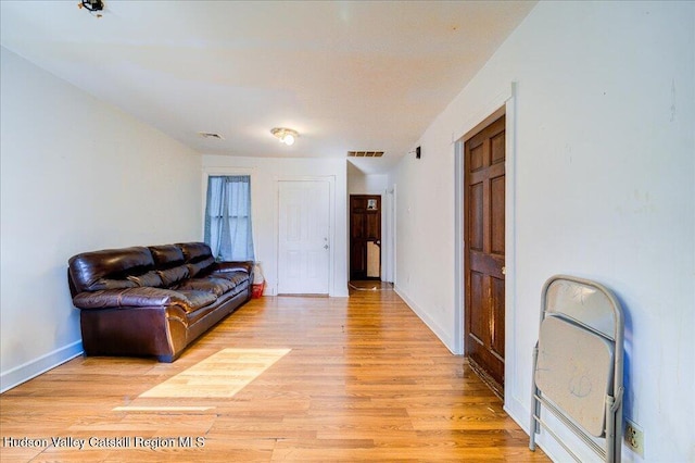 living area with light wood-style floors, visible vents, and baseboards