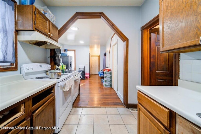 kitchen featuring white electric range oven, light tile patterned floors, baseboards, light countertops, and under cabinet range hood