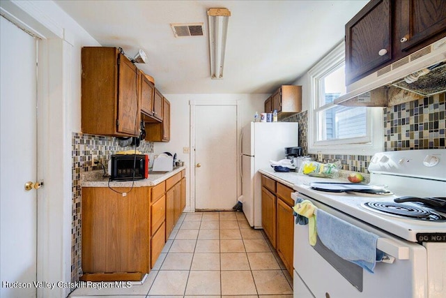 kitchen featuring light tile patterned floors, white appliances, visible vents, light countertops, and decorative backsplash