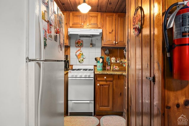 7951 State Route 22, Copake, NY 12516 - kitchen with white appliances, under cabinet range hood, brown cabinetry, tasteful backsplash, and wooden ceiling