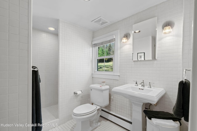 full bath with tile walls, toilet, a baseboard heating unit, tile patterned flooring, and a tile shower
