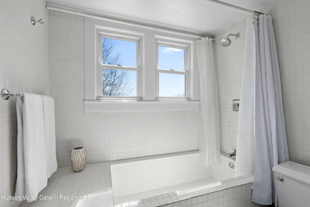 bathroom featuring tile walls, toilet, and tiled shower / bath