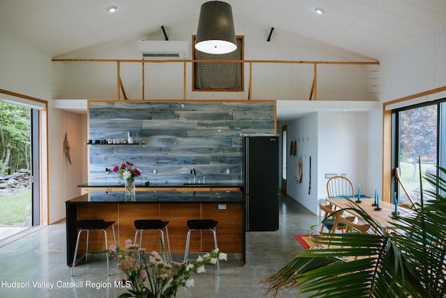 1199 W Highland Rd, Hobart, NY 13788 - kitchen with concrete flooring, freestanding refrigerator, high vaulted ceiling, a wall unit AC, and plenty of natural light
